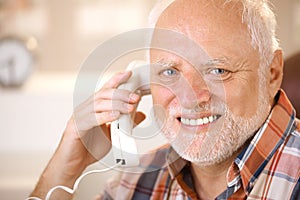 Portrait of smiling senior using landline phone photo