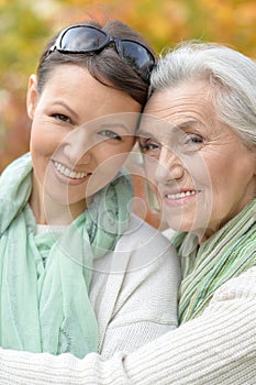 Portrait of smiling senior woman with adult daughter in autumnal park