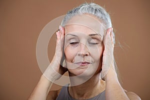 Portrait of smiling senior woman with closed eyes in studio.