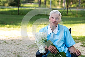 Portrait of smiling senior woman garndmother holding a purple flower pot outdoors