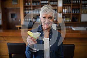 Senior woman having glass of cocktail in bar