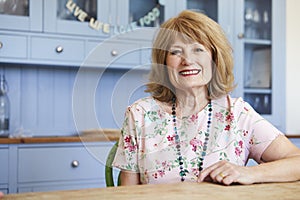 Portrait Of Smiling Senior Woman At Home Sitting At Table