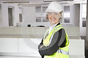 Portrait of smiling senior woman in reflector vest and hard hat at office