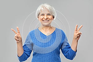 Portrait of smiling senior woman showing peace