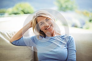 Portrait of smiling senior woman sitting on sofa in living room