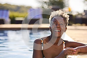 Portrait Of Smiling Senior Woman On Summer Holiday Relaxing In Swimming Pool