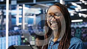 Portrait of smiling server room engineer using device to interpret AI data