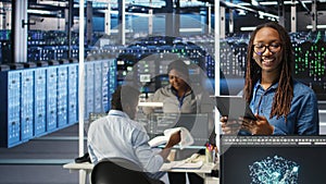 Portrait of smiling server room engineer using device to interpret AI data