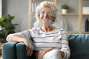Portrait of smiling sincere mature woman relaxing on comfortable sofa.