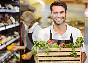 Portrait of a smiling staff man holding a box of fresh vegetables photo