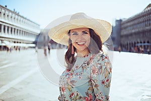 Portrait of smiling stylish traveller woman in floral dress photo