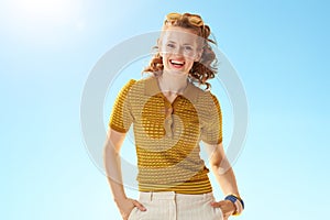 Portrait of smiling stylish woman against blue sky