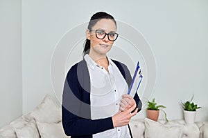 Portrait of smiling successful business woman wearing glasses with papers