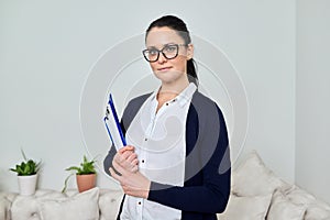 Portrait of smiling successful business woman wearing glasses with papers