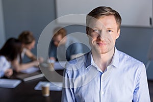 Portrait of smiling successful company ceo with team at backgrou