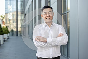 Portrait of a smiling and successful young businessman, office worker in a white shirt standing outside on the street