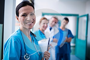 Portrait of smiling surgeon holding a clipboard in corridor
