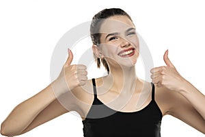 Portrait of a smiling teen girl with tied hair showing thumbs up