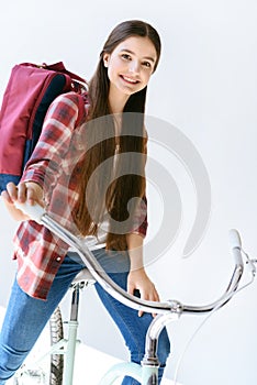 portrait of smiling teenage girl with backpack sitting on bicycle