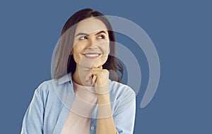 Portrait of smiling thinkful brunette woman in light blue shirt posing on blue background.