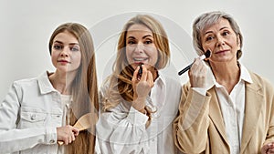 Portrait of smiling three generations of women do makeup