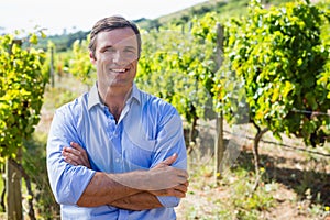 Portrait of smiling vintner standing with arms crossed