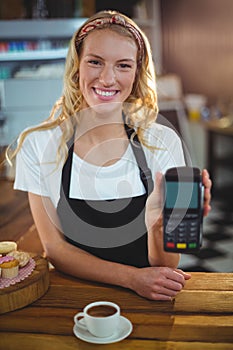 Portrait of smiling waitress holding credit card reader