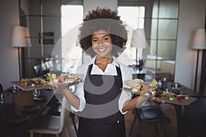 Portrait of smiling waitress holding food tray photo