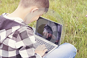 Cheerful teenager chatting on modern laptop