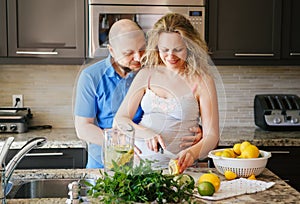 Portrait of smiling white Caucasian couple two people pregnant woman with husband cooking food