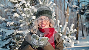 Portrait smiling woman blowing snowflakes snow particles at sunny winter forest closeup slow motion