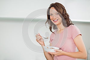 Portrait of smiling woman with a bowl of cereals at home