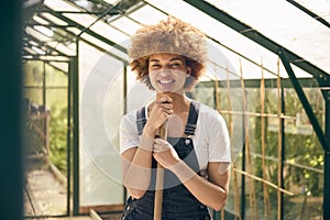 Portrait Of Smiling Woman With Broom Working In Greenhouse At Home