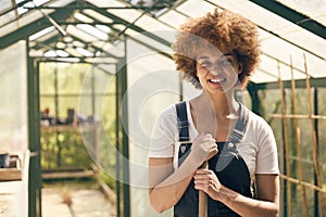 Portrait Of Smiling Woman With Broom Working In Greenhouse At Home