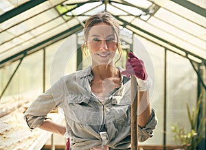 Portrait Of Smiling Woman With Broom Working In Greenhouse At Home