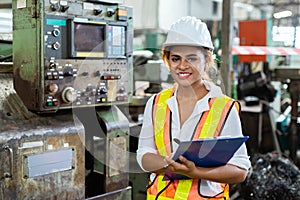 Portrait of smiling woman engineer industry worker wearing hardhat and holding cardboard looking camera.