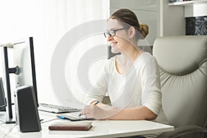 Portrait of smiling young woman in eyeglasses working in office and using graphic tablet