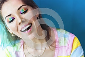 Portrait of a smiling woman girl with rainbow colored bright eye makeup in a multicolor blouse. The woman`s eyes are