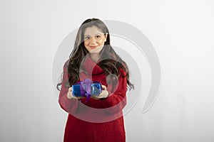 Portrait of a smiling woman giving a Christmas gift box with purple ribbon