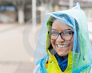 Portrait of a smiling woman with glasses wearing a raincoat outdoors.