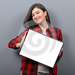 Portrait of smiling woman holding blank sign board.Studio portrait of young woman with sign card against gray background