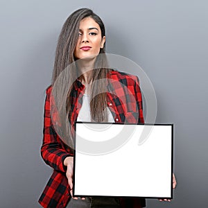 Portrait of smiling woman holding blank sign board.Studio portrait of young woman with sign card against gray background