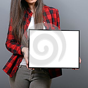 Portrait of smiling woman holding blank sign board.Studio portrait of young woman with sign card against gray background