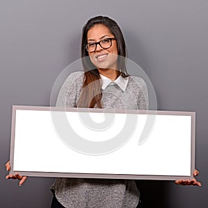 Portrait of smiling woman holding blank sign board.Studio portrait of young woman with sign card against gray background