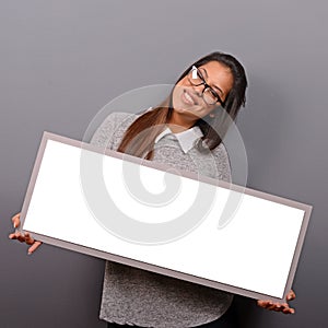 Portrait of smiling woman holding blank sign board.Studio portrait of young woman with sign card against gray background