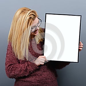 Portrait of smiling woman holding blank sign board.Studio portrait of young woman with sign card against gray background