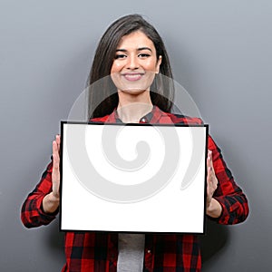 Portrait of smiling woman holding blank sign board.Studio portrait of young woman with sign card against gray background