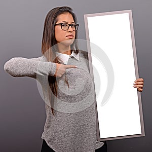 Portrait of smiling woman holding blank sign board.Studio portrait of young woman with sign card against gray background