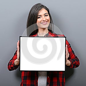 Portrait of smiling woman holding blank sign board.Studio portrait of young woman with sign card against gray background