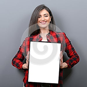 Portrait of smiling woman holding blank sign board.Studio portrait of young woman with sign card against gray background